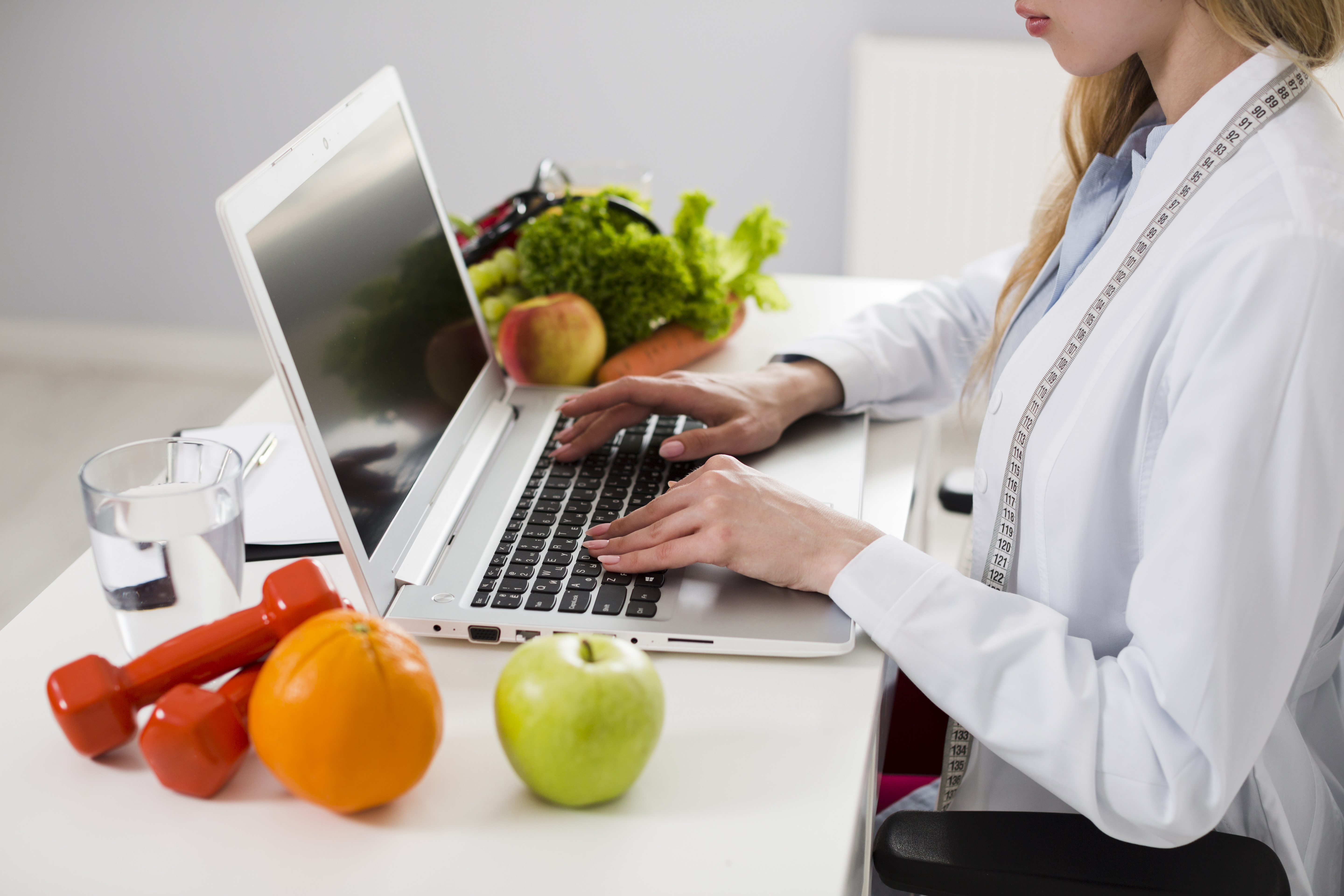 Mujer trabajando con una laptop rodeada de frutas y verduras